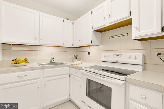 kitchen with sink, white electric stove, light tile patterned floors, tasteful backsplash, and white cabinetry