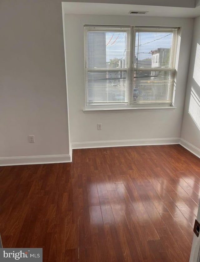 spare room featuring a wealth of natural light, dark wood-style flooring, and visible vents