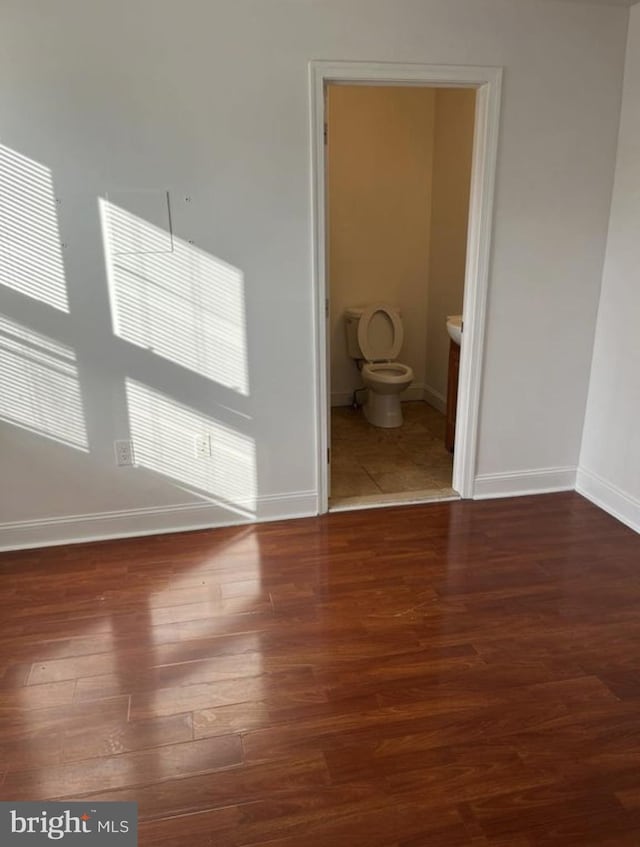 spare room featuring dark wood-style flooring and baseboards