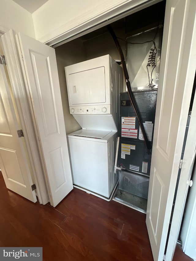 laundry area featuring laundry area, dark wood-type flooring, and stacked washer / drying machine