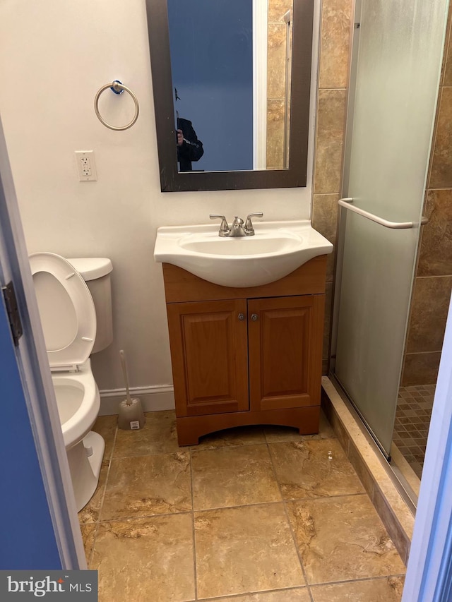 full bathroom featuring a stall shower, vanity, toilet, and baseboards