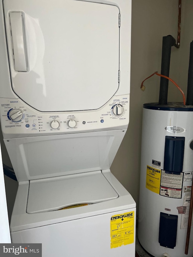 clothes washing area with laundry area, electric water heater, and stacked washer / drying machine