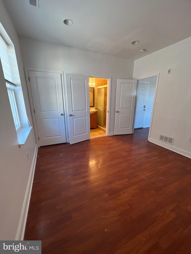 unfurnished bedroom featuring dark wood-style flooring, visible vents, and baseboards