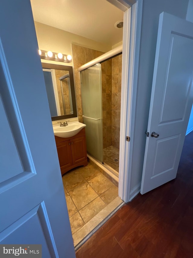 full bath with a shower stall, vanity, and wood finished floors