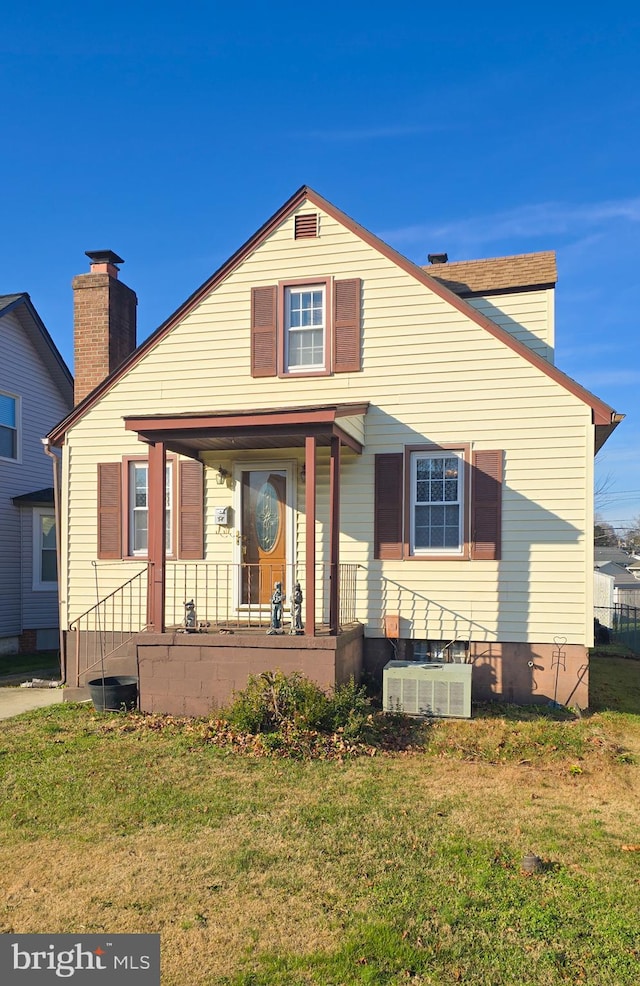 bungalow-style house with a front yard, a porch, and cooling unit