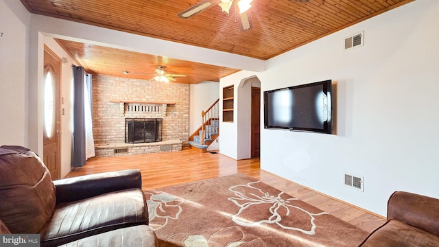 living room with ceiling fan, light wood-type flooring, a fireplace, and wooden ceiling