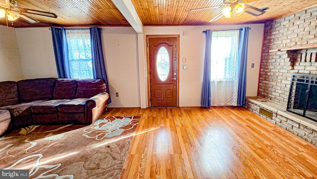 unfurnished living room with light wood-type flooring, a brick fireplace, ornamental molding, ceiling fan, and wooden ceiling