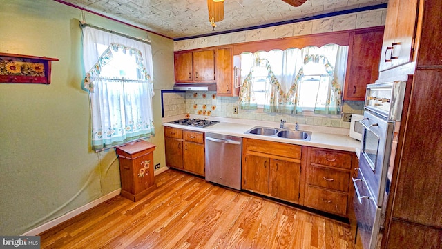 kitchen with ceiling fan, sink, stainless steel appliances, light hardwood / wood-style flooring, and ornamental molding