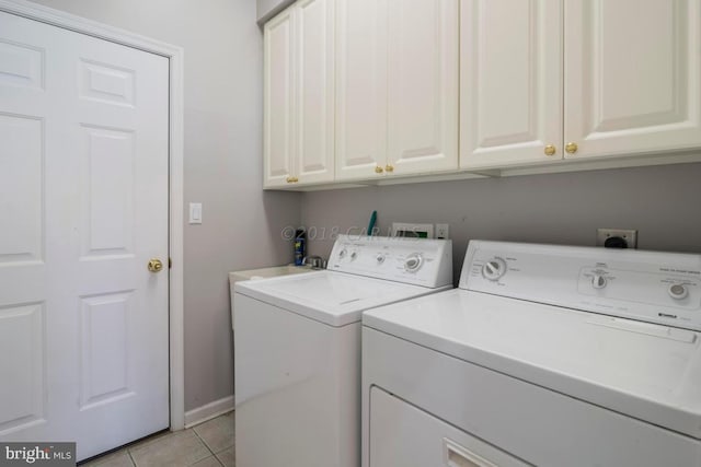 laundry area with washing machine and dryer, light tile patterned floors, and cabinets