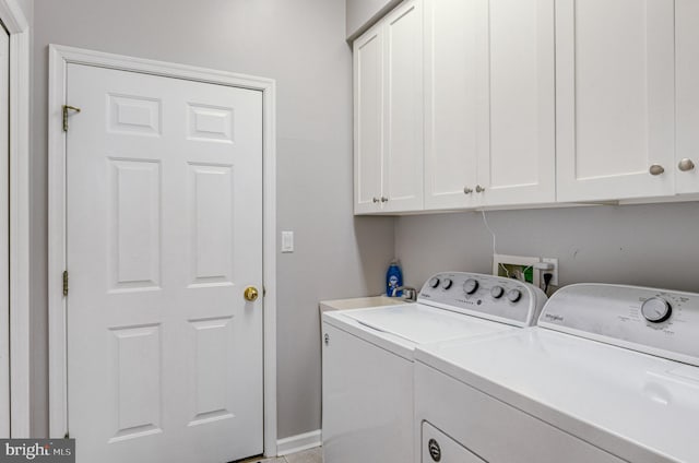 laundry room featuring washer and clothes dryer and cabinets