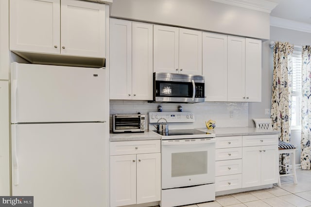 kitchen with white appliances, light tile patterned floors, backsplash, white cabinets, and ornamental molding