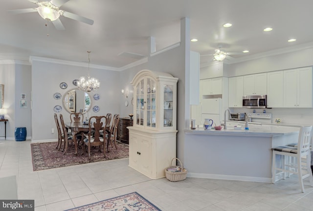 kitchen featuring white appliances, light tile patterned floors, crown molding, ceiling fan with notable chandelier, and white cabinets