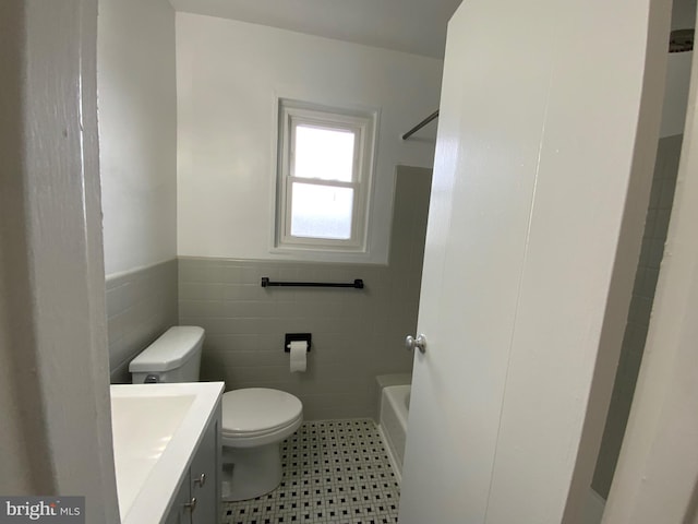 full bathroom featuring shower with separate bathtub, vanity, tile walls, and toilet