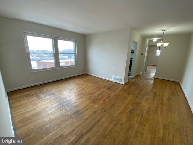 spare room featuring hardwood / wood-style flooring and a notable chandelier