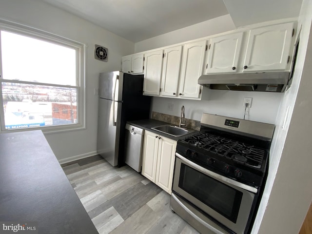 kitchen with appliances with stainless steel finishes, light hardwood / wood-style flooring, white cabinetry, and sink