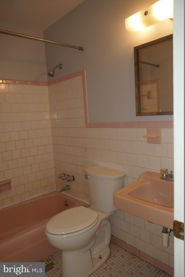 full bathroom featuring tile patterned floors, tiled shower / bath, tile walls, and toilet