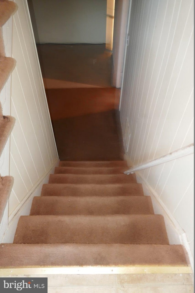 stairway featuring wood walls