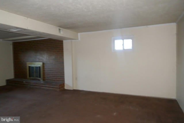 basement featuring a textured ceiling, a brick fireplace, and crown molding