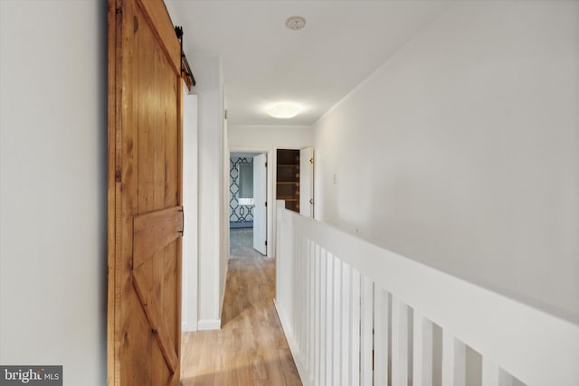 hallway with a barn door and light wood-type flooring