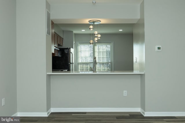 kitchen featuring black refrigerator, pendant lighting, kitchen peninsula, and sink