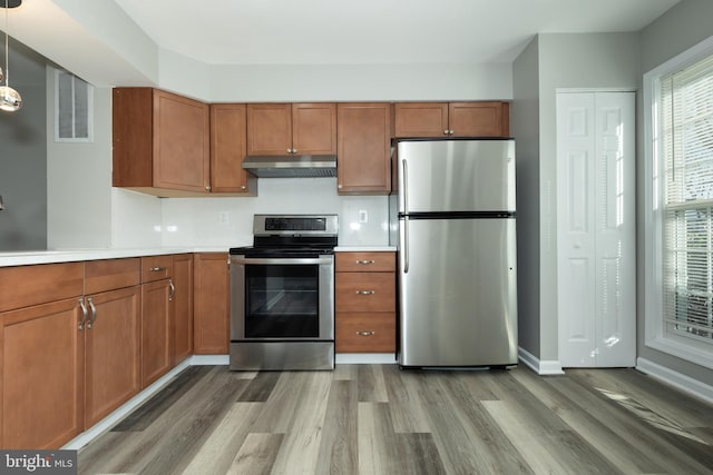 kitchen with wood-type flooring, stainless steel appliances, and hanging light fixtures