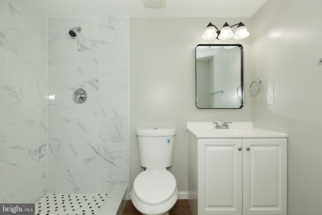 bathroom featuring vanity, toilet, and a tile shower