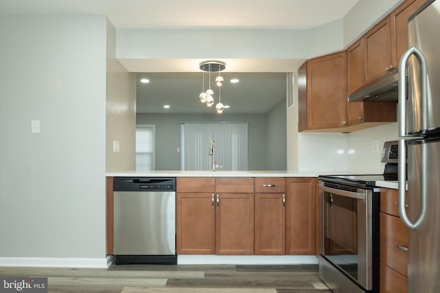 kitchen featuring sink, backsplash, pendant lighting, exhaust hood, and appliances with stainless steel finishes