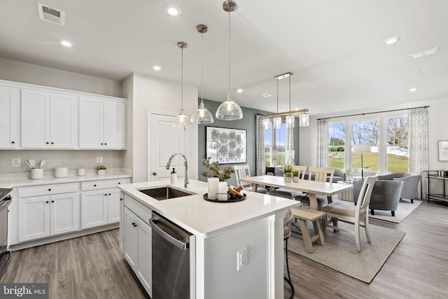 kitchen featuring stainless steel dishwasher, sink, decorative light fixtures, a center island with sink, and white cabinets