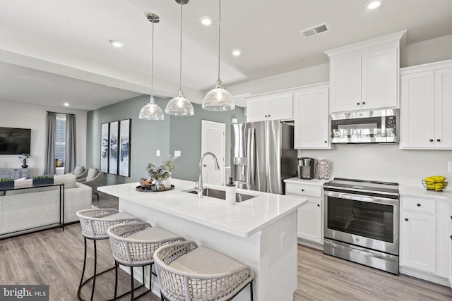 kitchen with a center island with sink, decorative light fixtures, sink, and stainless steel appliances