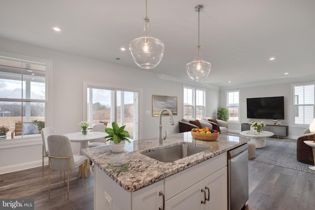 kitchen featuring light stone counters, stainless steel dishwasher, sink, pendant lighting, and white cabinetry