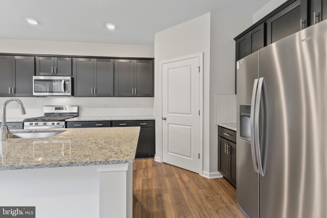 kitchen featuring tasteful backsplash, light stone countertops, dark hardwood / wood-style floors, and appliances with stainless steel finishes