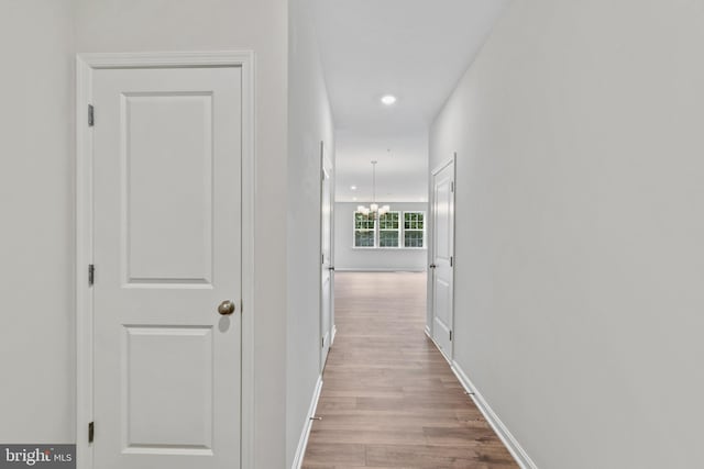 hall with light hardwood / wood-style flooring and an inviting chandelier