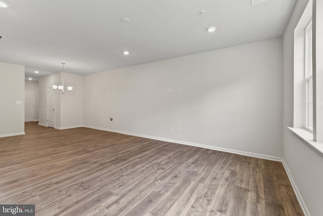 unfurnished room with a notable chandelier and light hardwood / wood-style floors