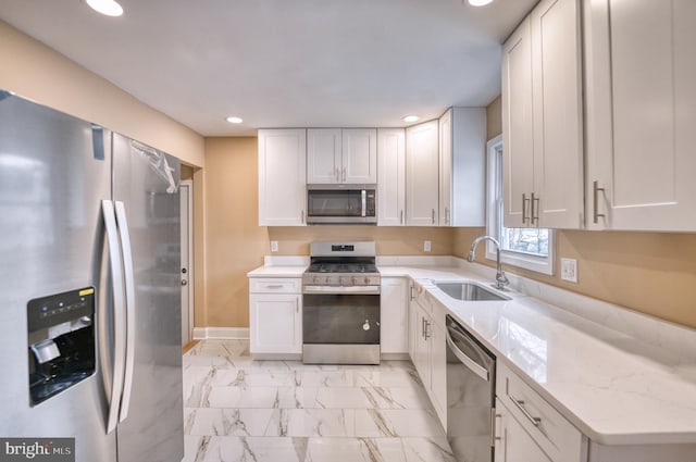 kitchen featuring stainless steel appliances, white cabinetry, light stone counters, and sink