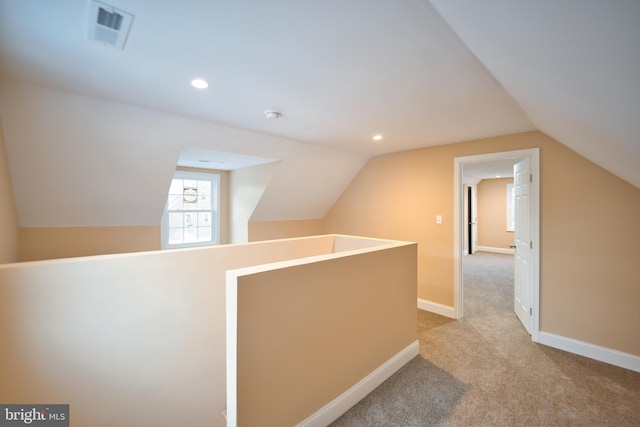 hall featuring light colored carpet and lofted ceiling