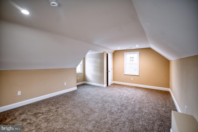 additional living space featuring vaulted ceiling and carpet floors