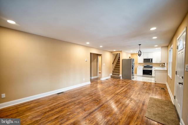 unfurnished living room featuring light wood-type flooring and sink