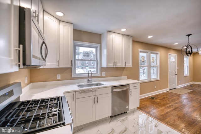 kitchen with sink, pendant lighting, white cabinets, and stainless steel appliances