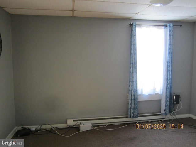 carpeted spare room with a paneled ceiling and a baseboard heating unit