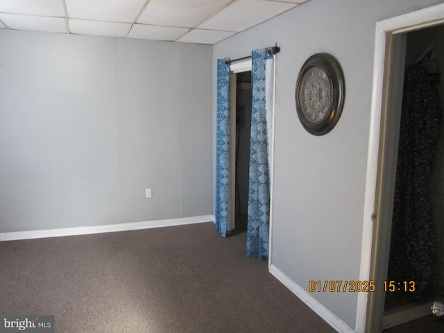 carpeted spare room featuring a drop ceiling