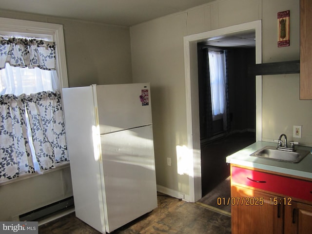 kitchen with white fridge, baseboard heating, and sink