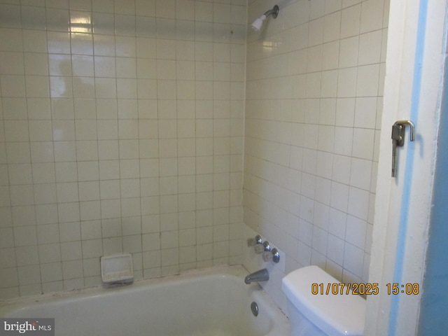 bathroom featuring tiled shower / bath combo and toilet