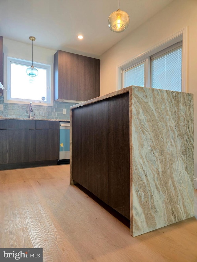 kitchen featuring stainless steel dishwasher, decorative light fixtures, modern cabinets, and light wood finished floors