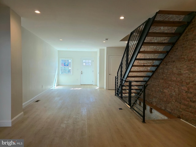 entrance foyer with recessed lighting, stairway, light wood-style floors, brick wall, and baseboards