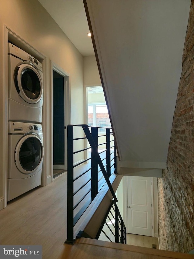 laundry area with laundry area, stacked washer and dryer, and wood finished floors