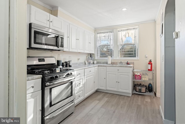 kitchen featuring white cabinetry, sink, stainless steel appliances, and light wood-type flooring