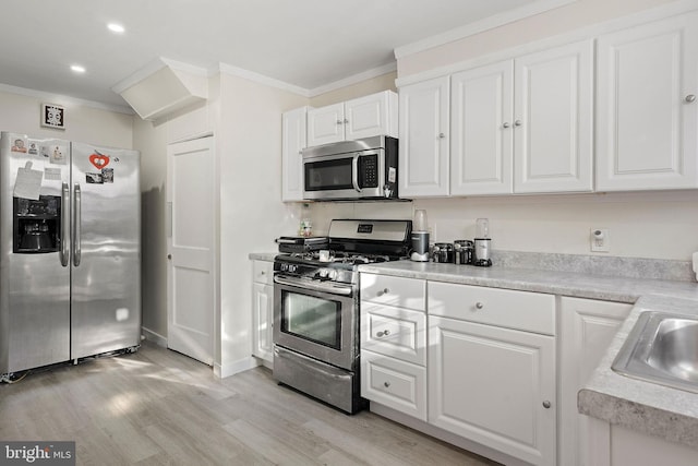 kitchen featuring sink, crown molding, appliances with stainless steel finishes, light hardwood / wood-style floors, and white cabinets