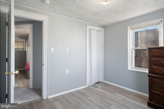 unfurnished bedroom with light wood-type flooring, a closet, and crown molding