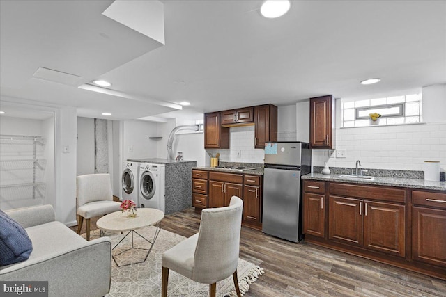 kitchen with washer and clothes dryer, backsplash, sink, dark hardwood / wood-style flooring, and stainless steel appliances