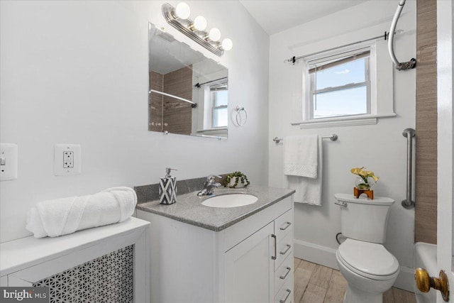 bathroom with toilet, vanity, a healthy amount of sunlight, and hardwood / wood-style flooring